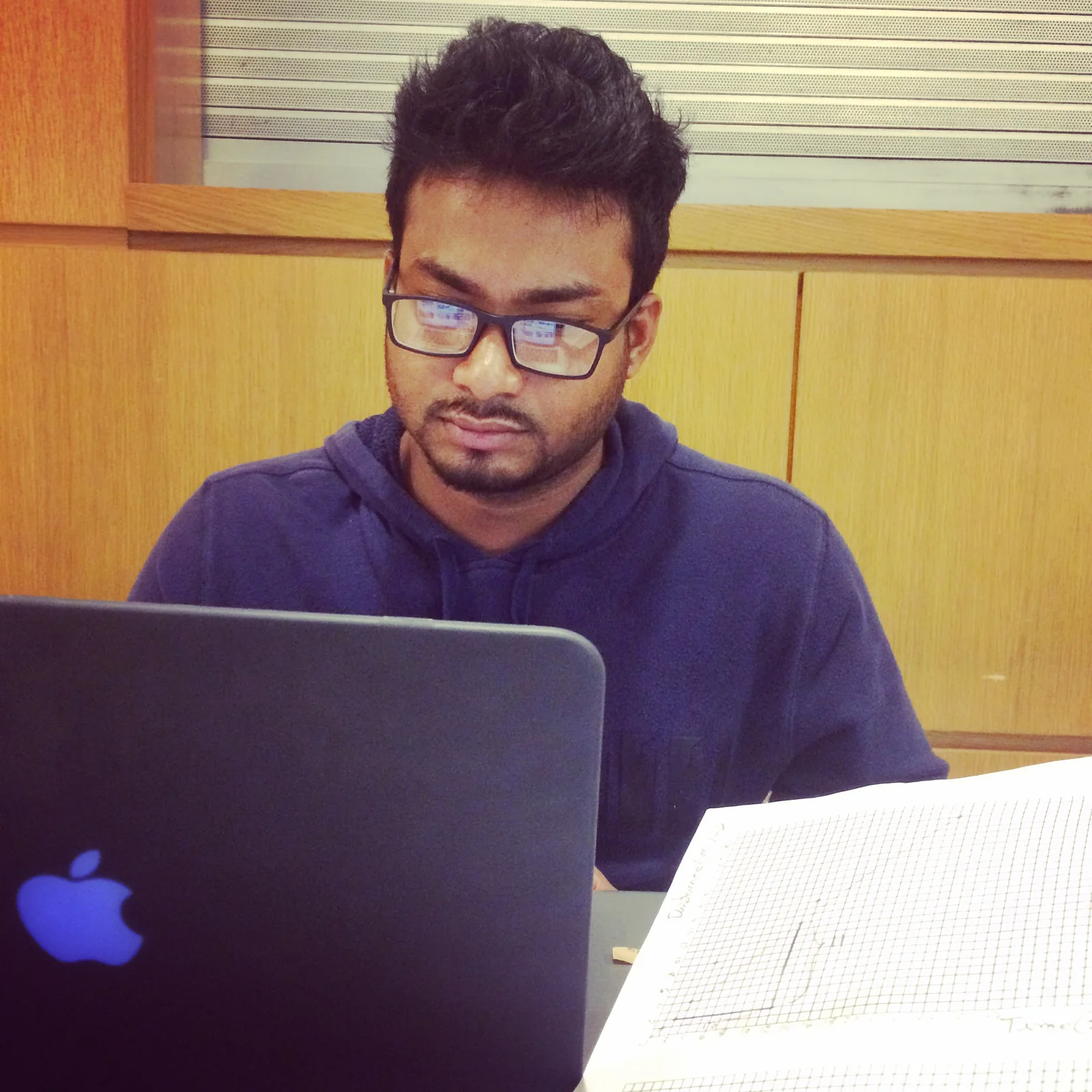 Shekh working at a laptop with notes beside him